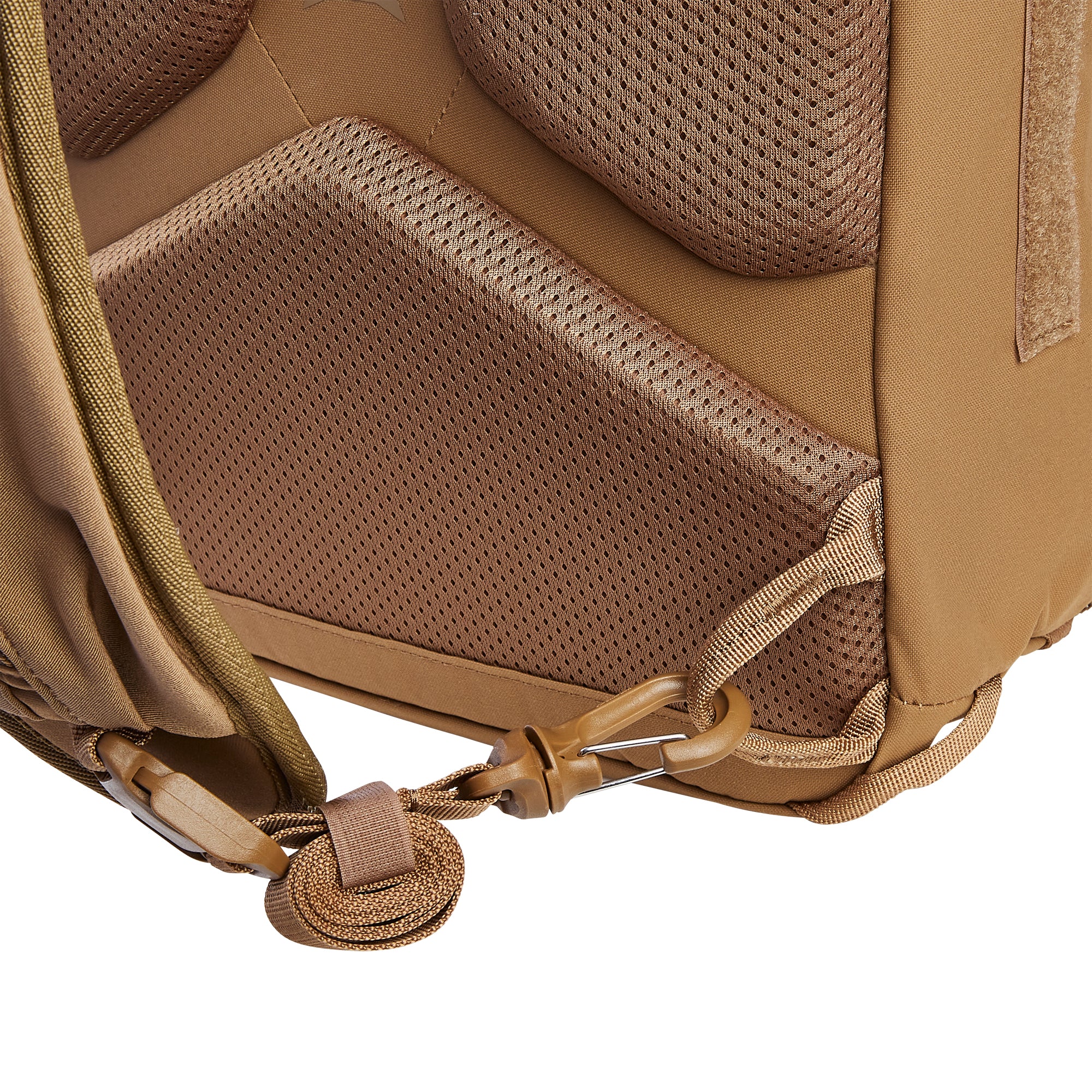 Close-up of a tan tactical backpack's lower back panel with breathable mesh padding, olive green webbing straps, and a coyote brown quick-release hook