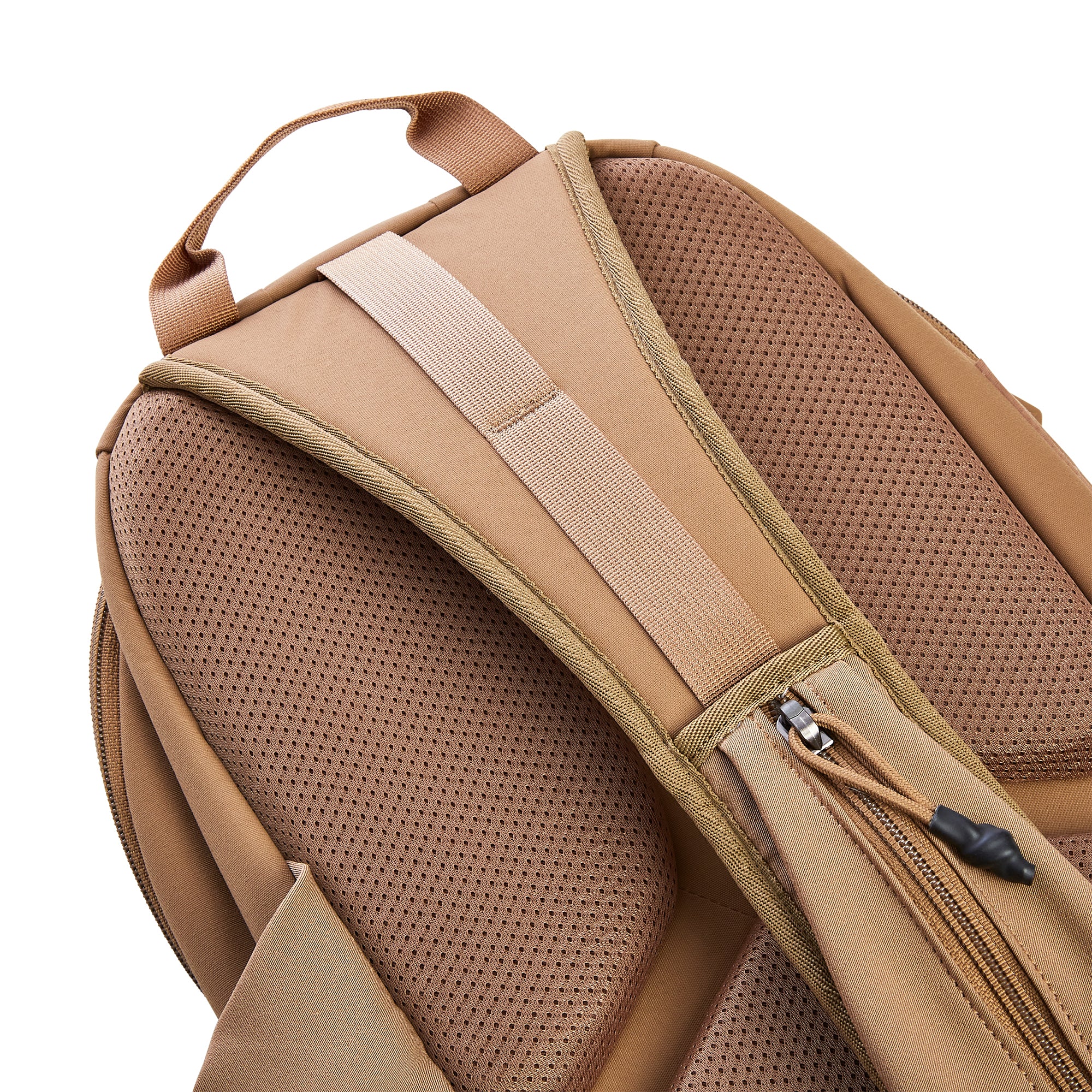 Photograph of a tan backpack's back panel featuring breathable perforated mesh padding a sturdy top handle and a zippered pocket with a black cord pull