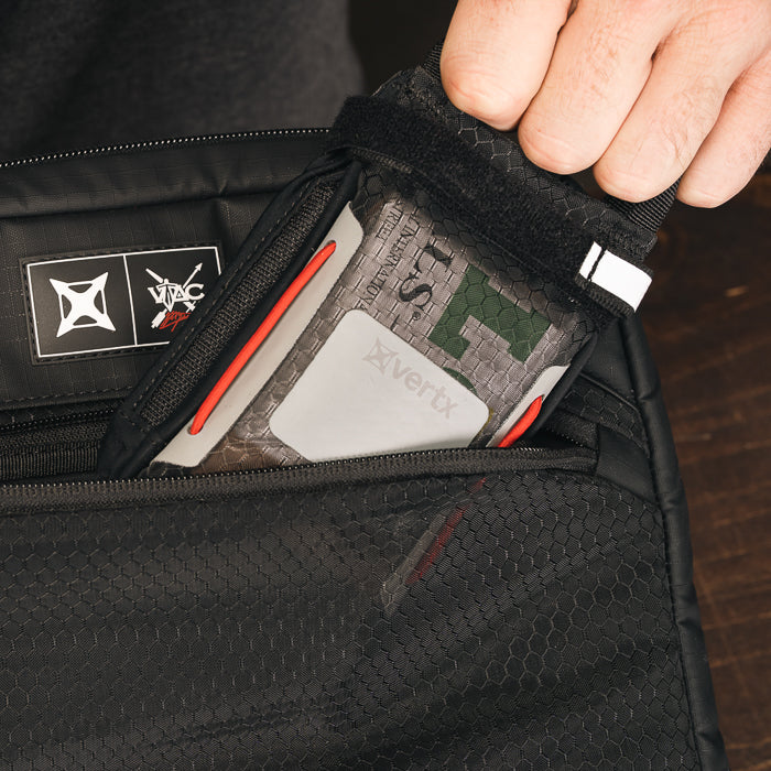 Product shot showing a Vertx bag with a grey and green first-aid kit featuring red accents and a white logo inside a black mesh pocket