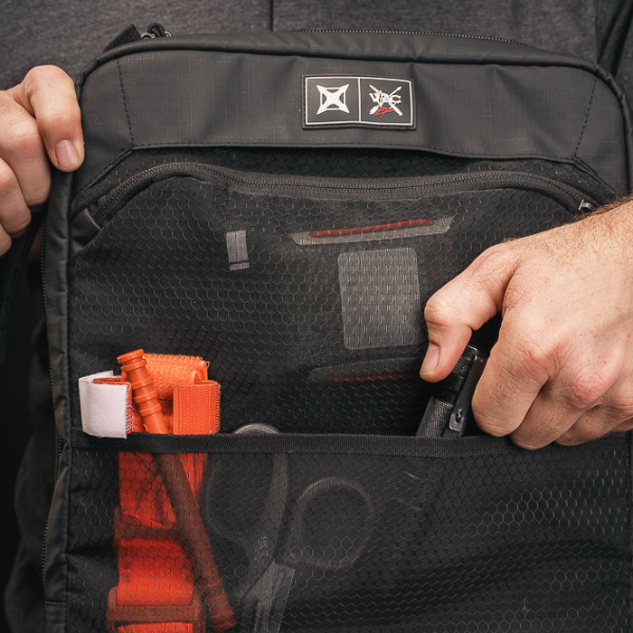 Product photography showing a black VAC bag with orange and gray items a mesh pocket and a logo