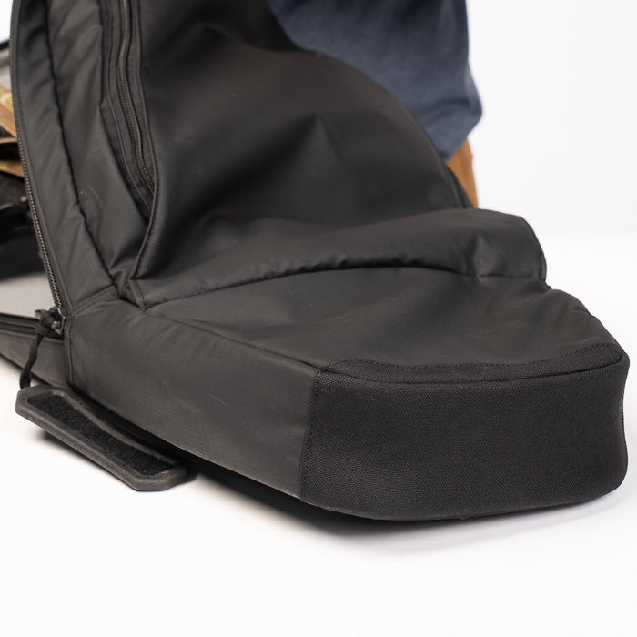 Product photography showing a black nylon backpack with a reinforced bottom a zippered pocket and adjustable straps on a white background