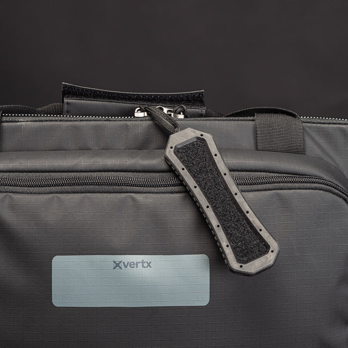 Product shot of a Vertx black bag featuring a textured zipper pull, a gray nameplate, and subtle stitching details
