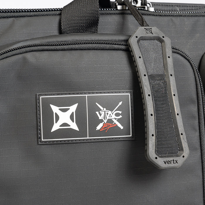 Close-up of a Vertx black tactical bag featuring a logo patch with geometric designs and the brand name a textured rubber handle and subtle stitching details