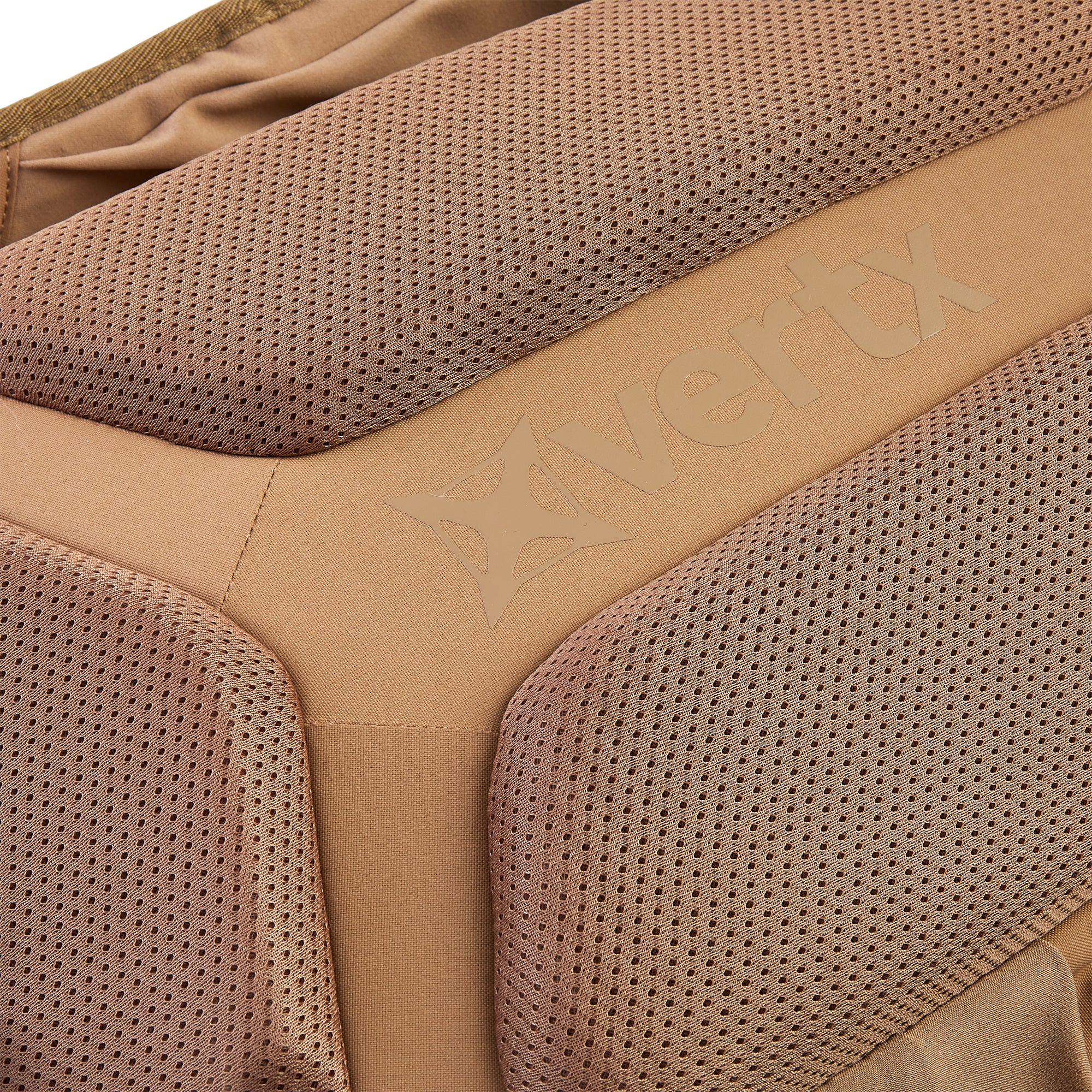 Close-up photograph of Vertx coyote brown tactical gear displaying perforated mesh padding and an embossed logo