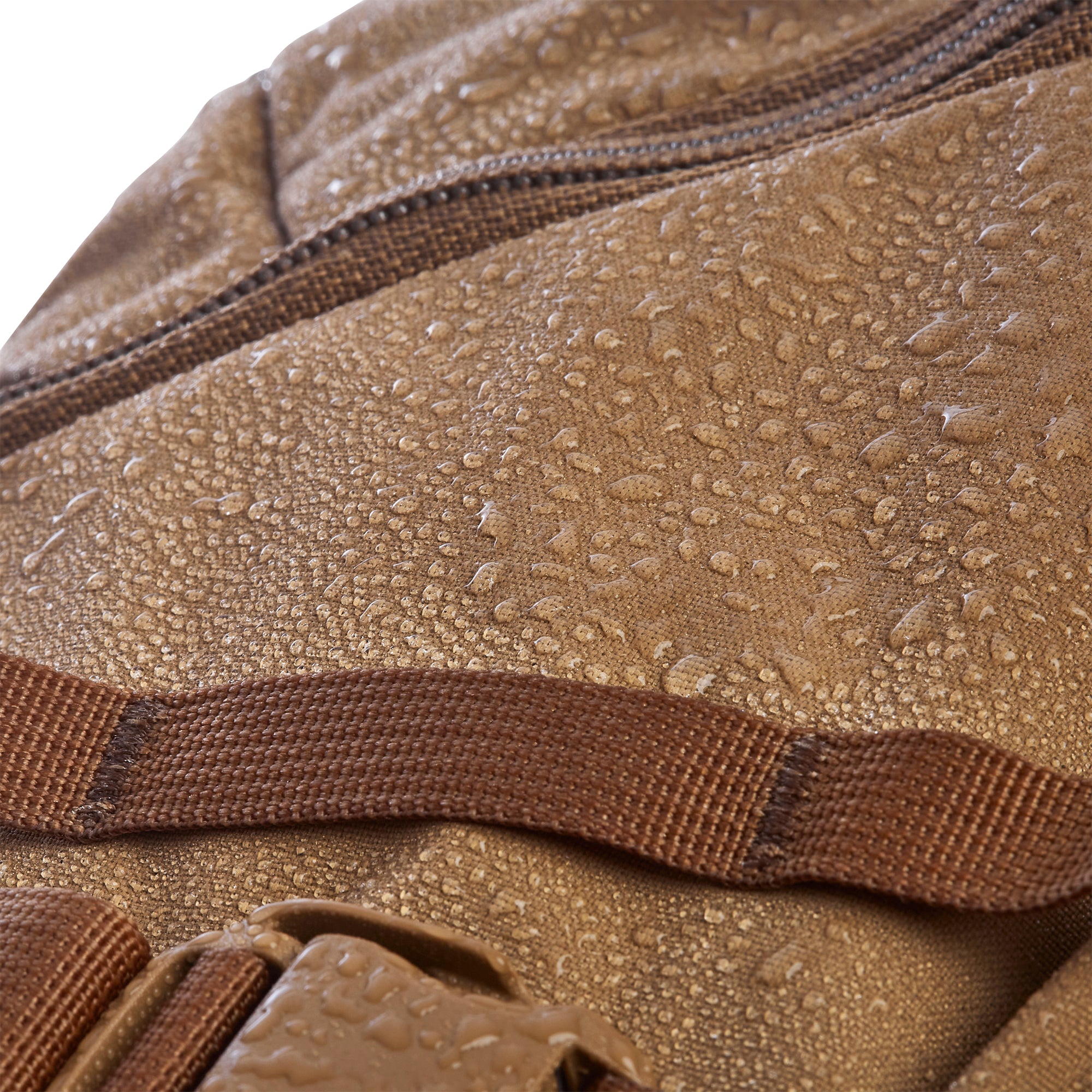 Macro shot of tan waterproof bag fabric covered in glistening water droplets featuring a brown zipper and darker brown webbing strap