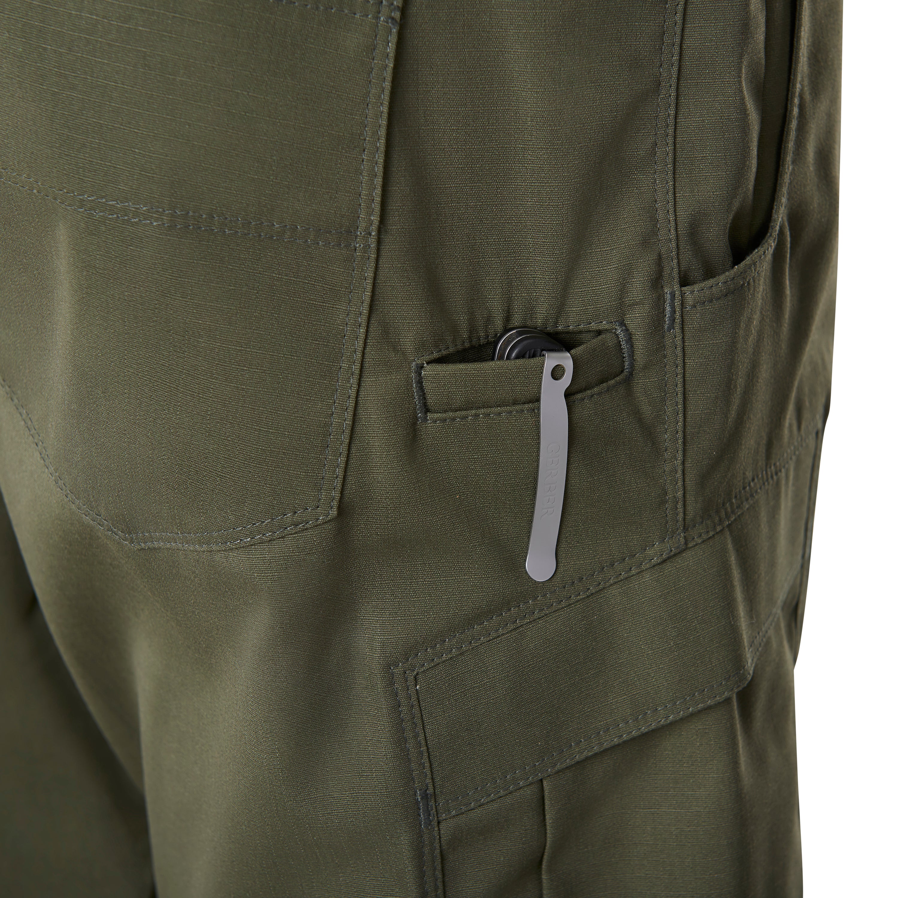 Close-up photograph of olive green cargo pants featuring a silver Gerber multi-tool in a pocket with visible dark stitching and textured fabric