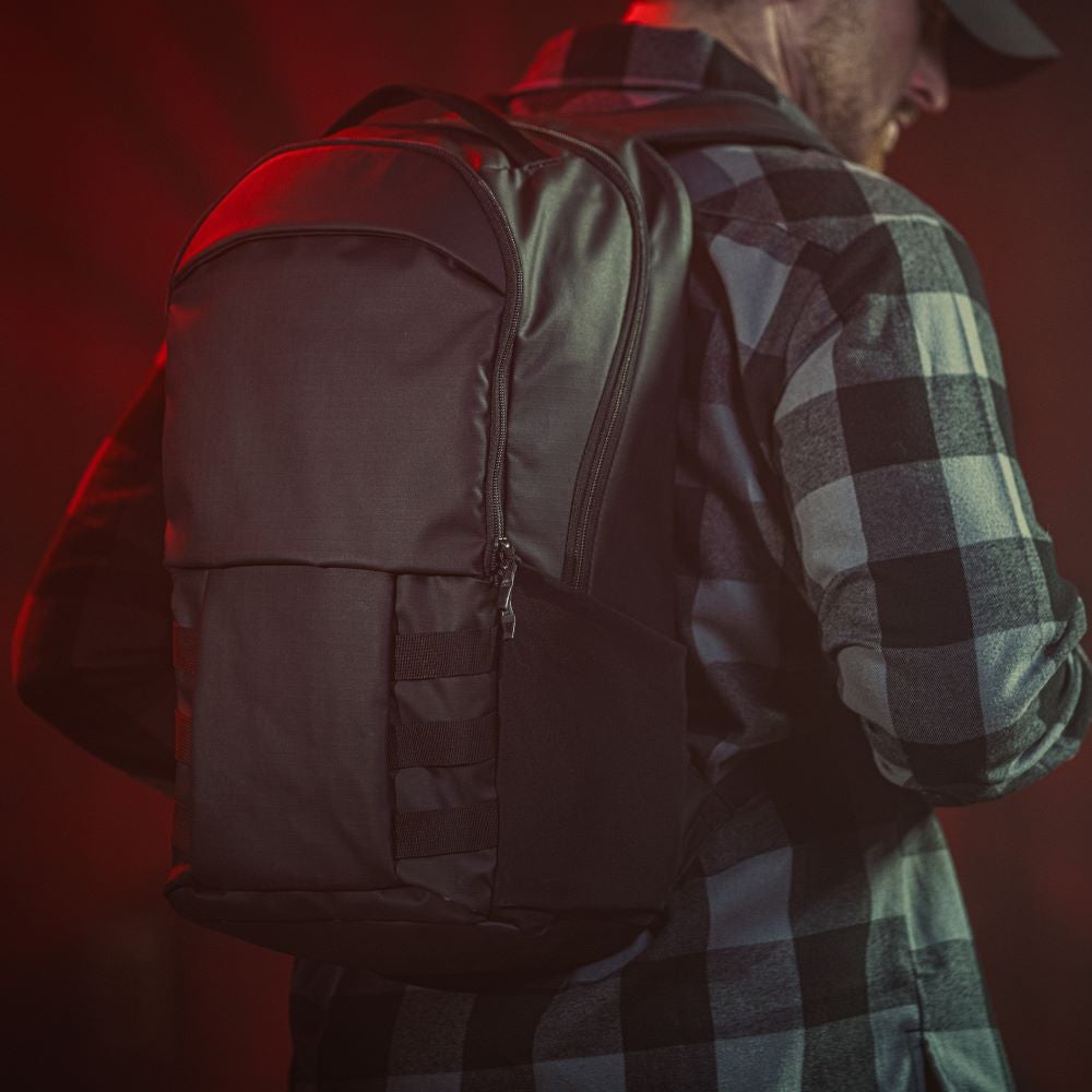Photography unknown artist a black backpack with sleek design and compression straps shown on a model against a red background featuring a matte finish and subtle zipper detailing