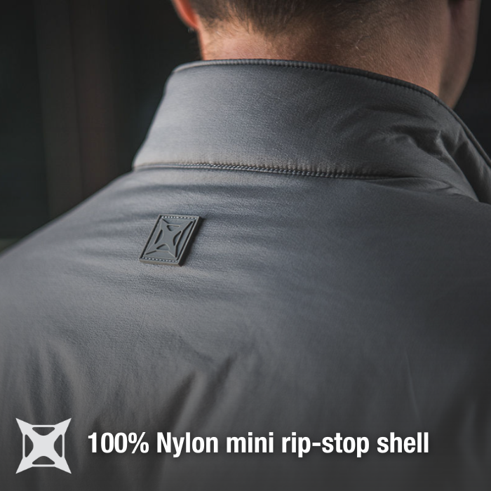 Product shot of a gray 100% nylon mini rip-stop shell jacket showing a dark gray logo patch on the back with subtle stitching detail and a high collar