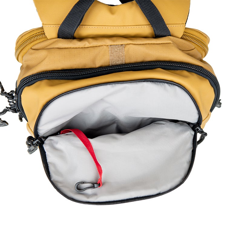 Product shot of a mustard-yellow backpack interior showcasing a gray lining a red key clip and black zippers