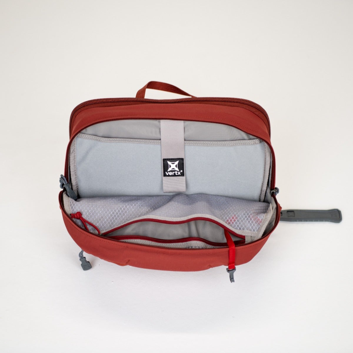 Product shot of a Vertx red and gray bag showing its interior organization with a main compartment, zippered pockets, and mesh dividers