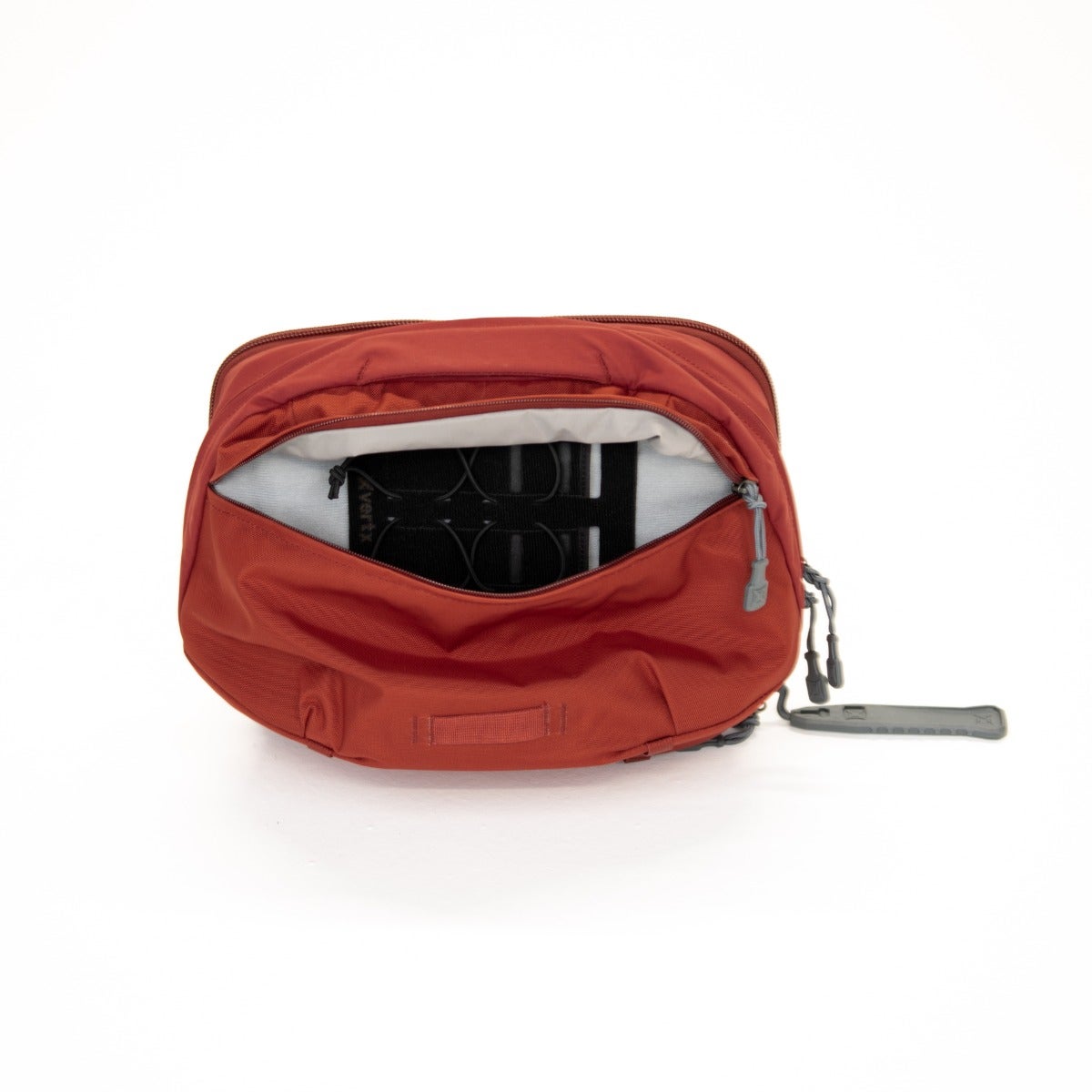 Product shot of a burnt orange backpack interior showing a gray padded back panel with black straps and a gray zipper pull