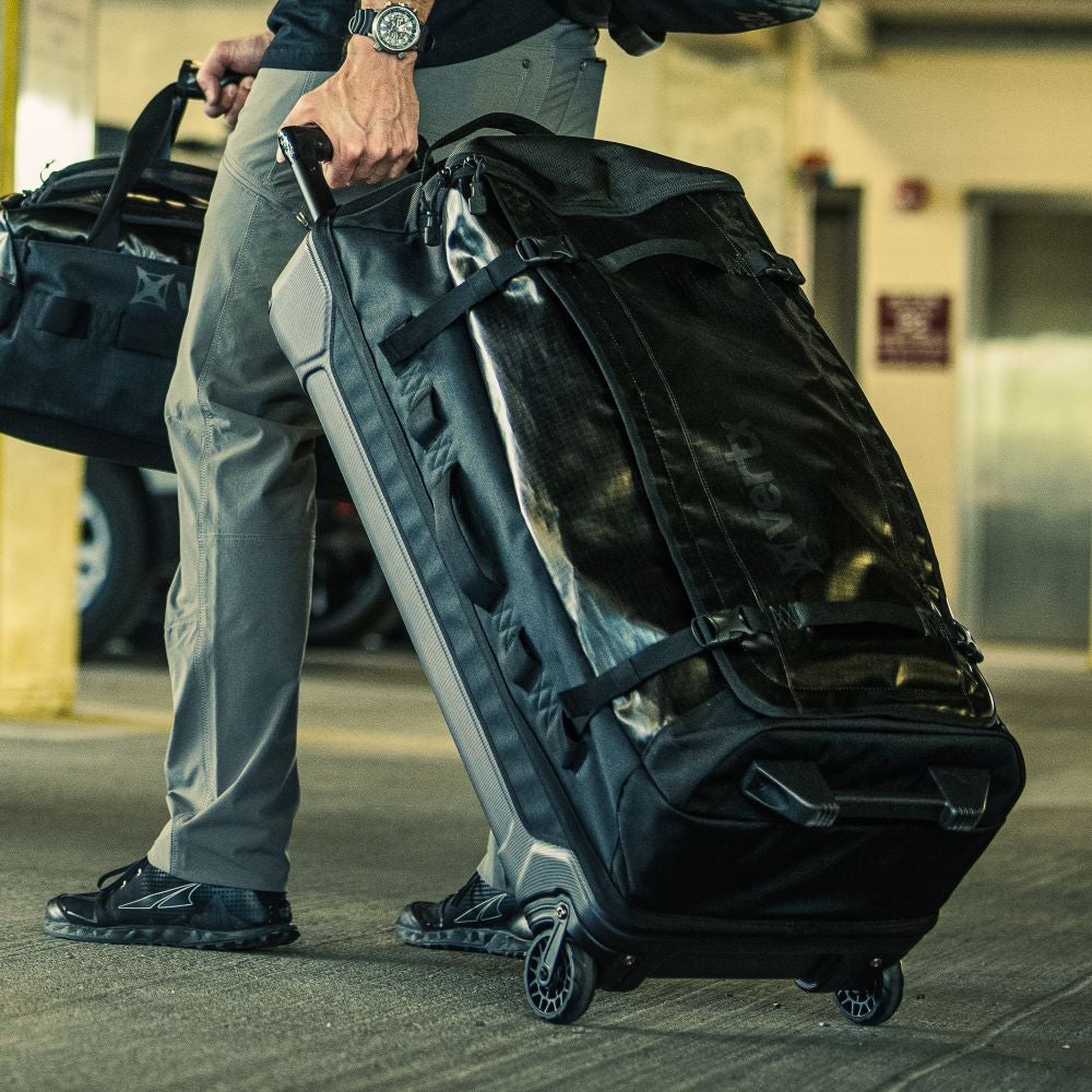 Avert wheeled duffel bag being rolled through a parking garage showing its black color, durable straps and textured fabric