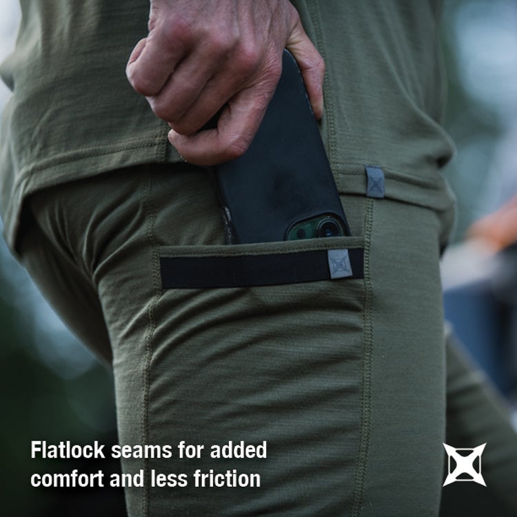 Close-up product shot of a person wearing olive-green merino wool pants with a phone in a secure pocket featuring flatlock seams and subtle gray detailing showing added comfort and reduced friction