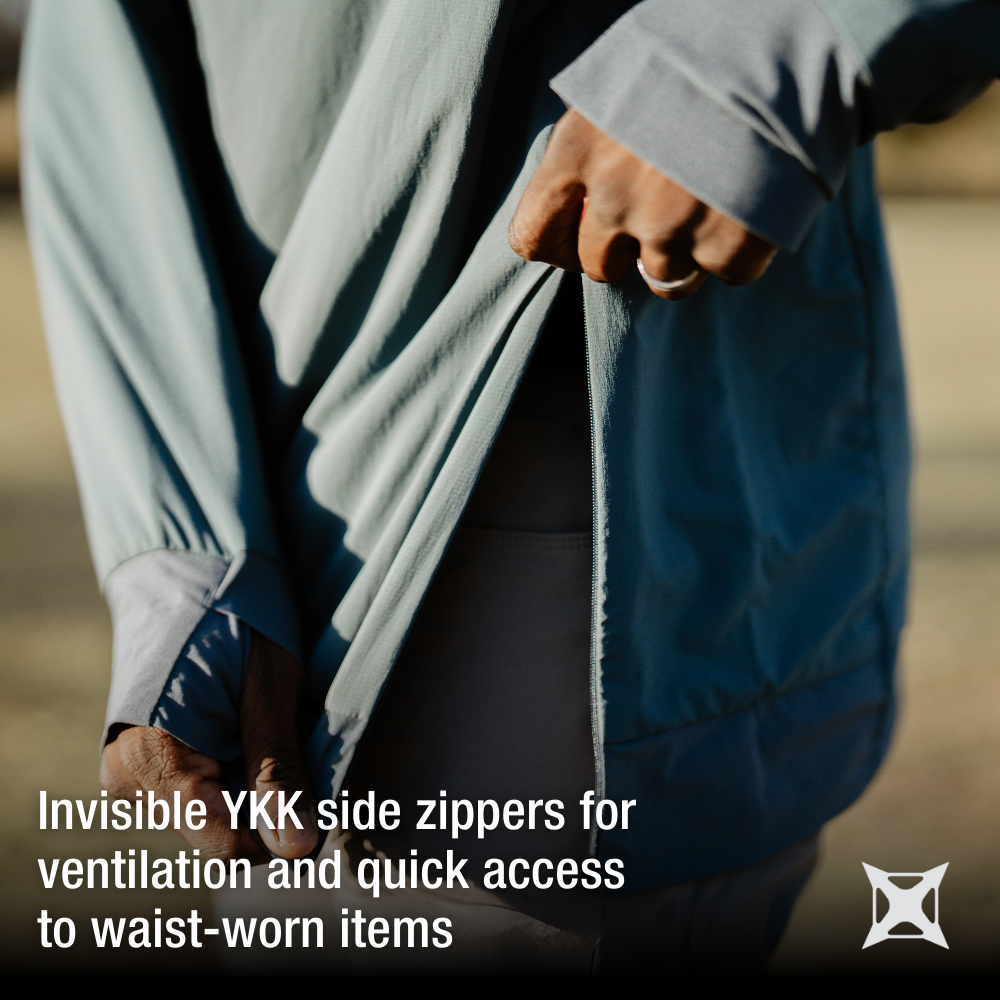 Photograph showing a person outdoors demonstrating a teal shirt with invisible YKK zippers and a beige waistband showing subtle texture and warm sunlight