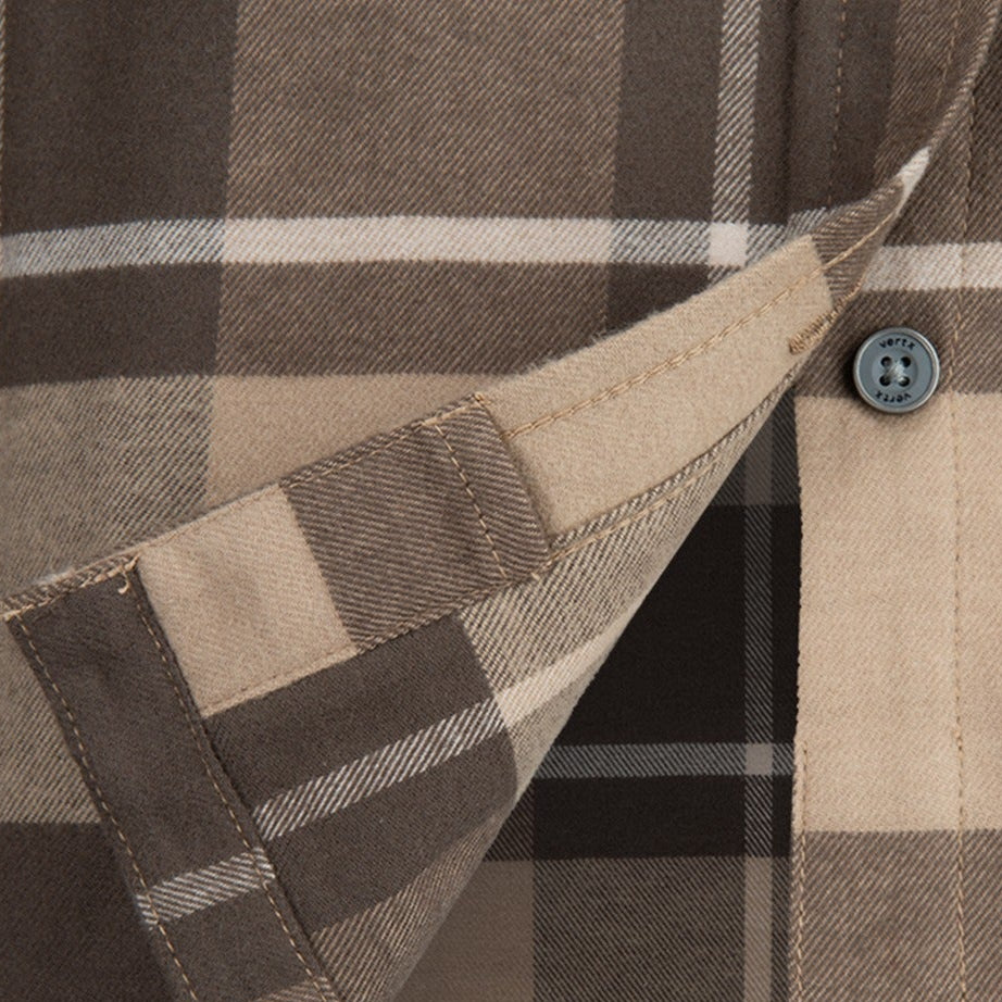 Close-up of a Vertx shirt showing a brown and beige plaid pattern with a visible button and contrasting stitching details
