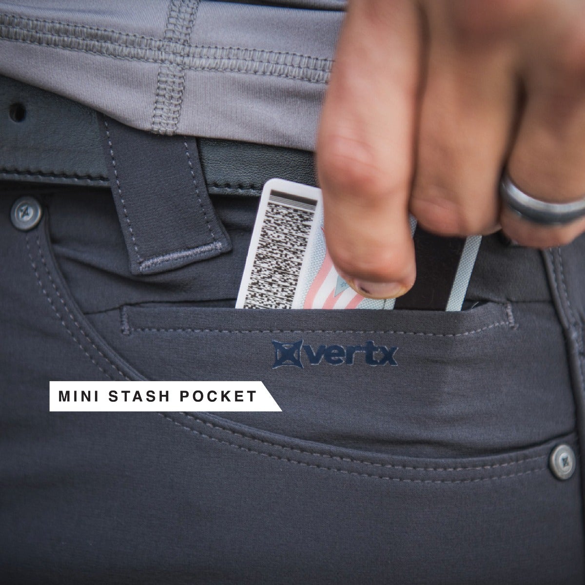 Product shot showing a hand placing an ID card into a dark gray Vertx mini stash pocket featuring subtle stitching and a branded logo