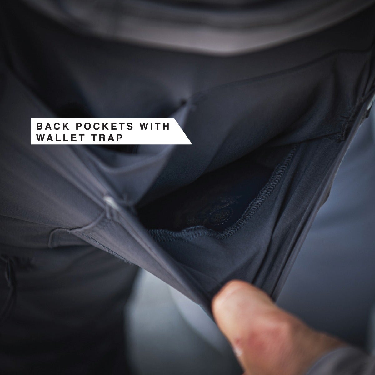 Close-up product shot showing dark gray fabric pants back pockets with a wallet trap featuring a secure, subtly textured interior and reinforced stitching