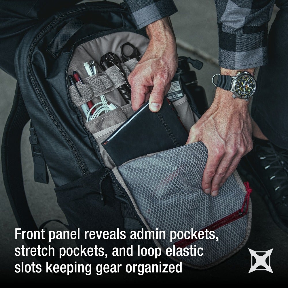 Product photography showing a person's hands accessing the many organized compartments of a black backpack featuring grey mesh, red accents, and a variety of tools and writing instruments
