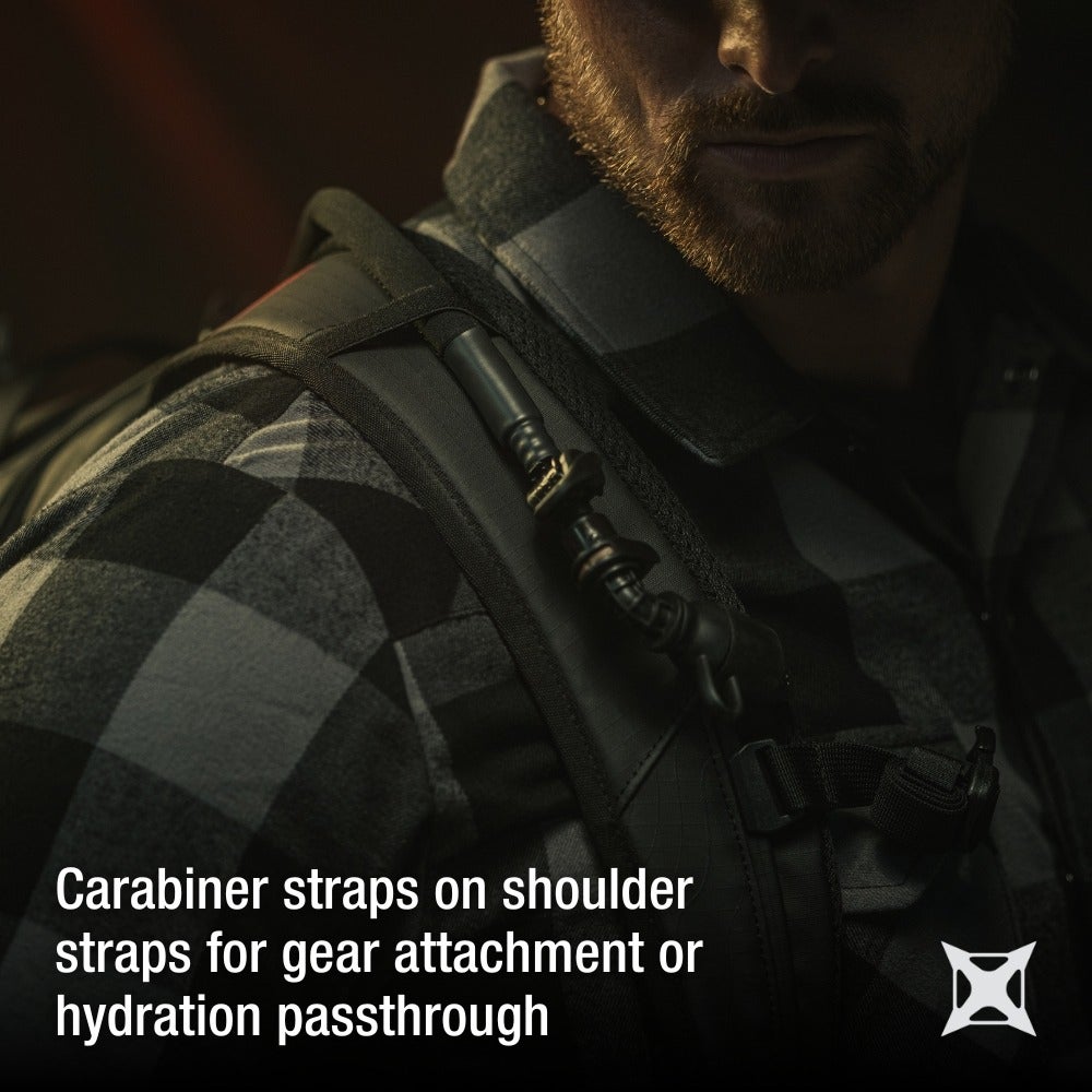 Product shot showing a man wearing a black backpack with carabiner straps and gray and black plaid shirt a black hydration tube and sturdy black buckles