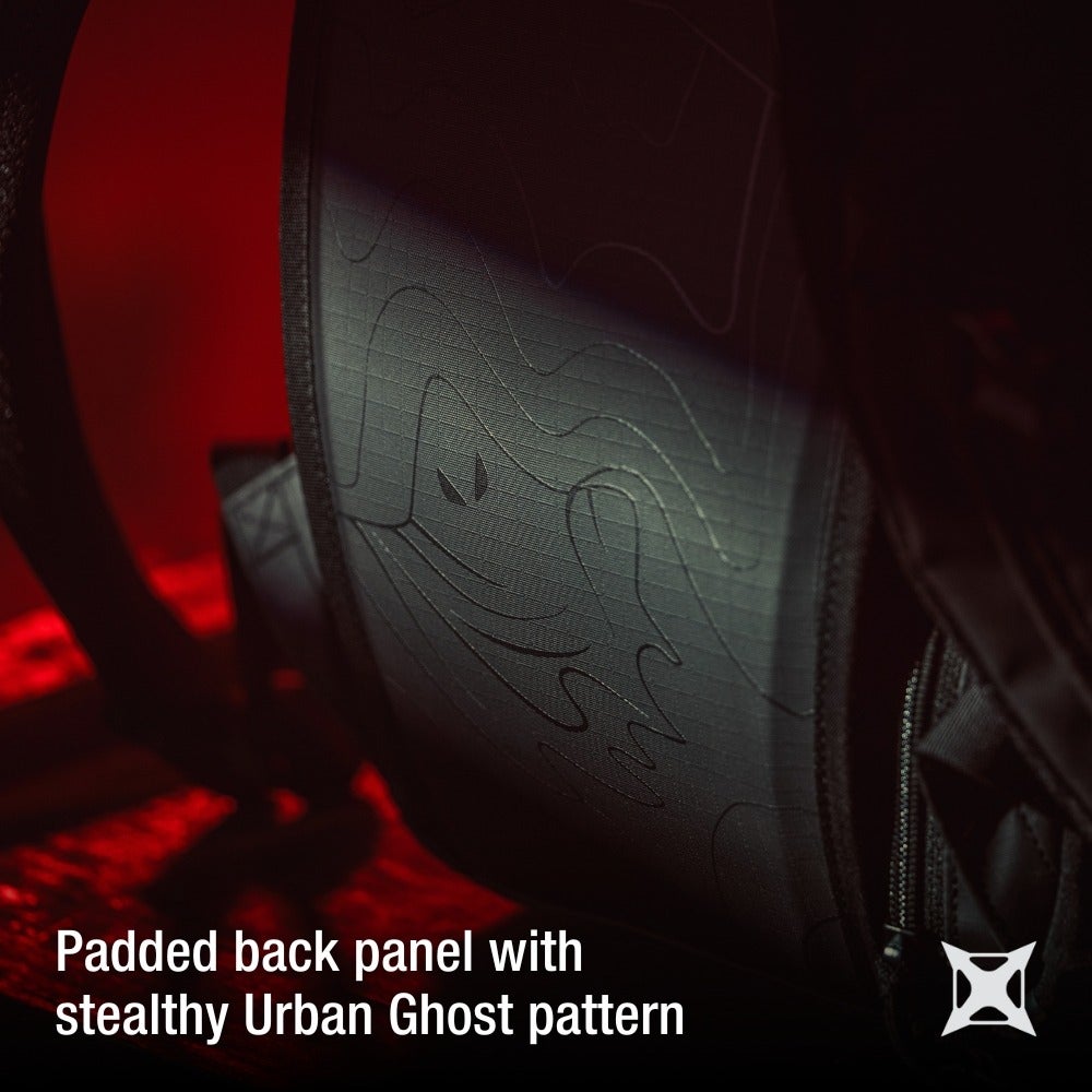 Product photography showing a close-up of a black backpack's padded back panel featuring a stealthy Urban Ghost pattern with embossed lines subtle shading and a three-point design detail
