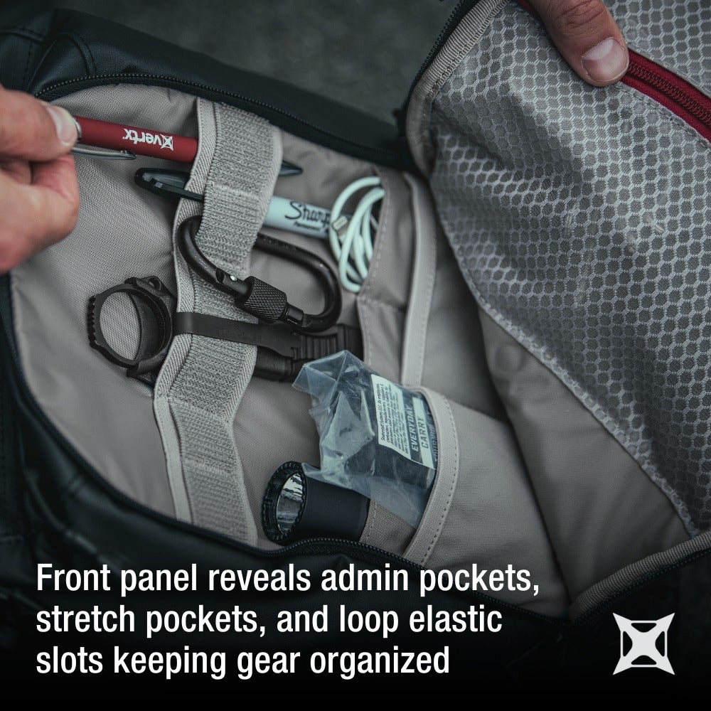 Product photography showing a black bag's interior with admin pockets, a red pen, and a carabiner, showcasing organizational features like stretch pockets and loop elastic slots