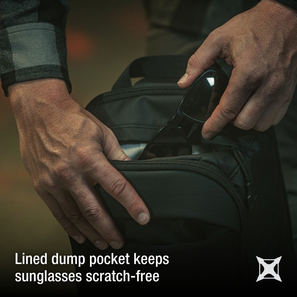 Product photography showing hands placing sunglasses into a dark gray lined dump pocket of a backpack featuring a zipper detail and soft interior