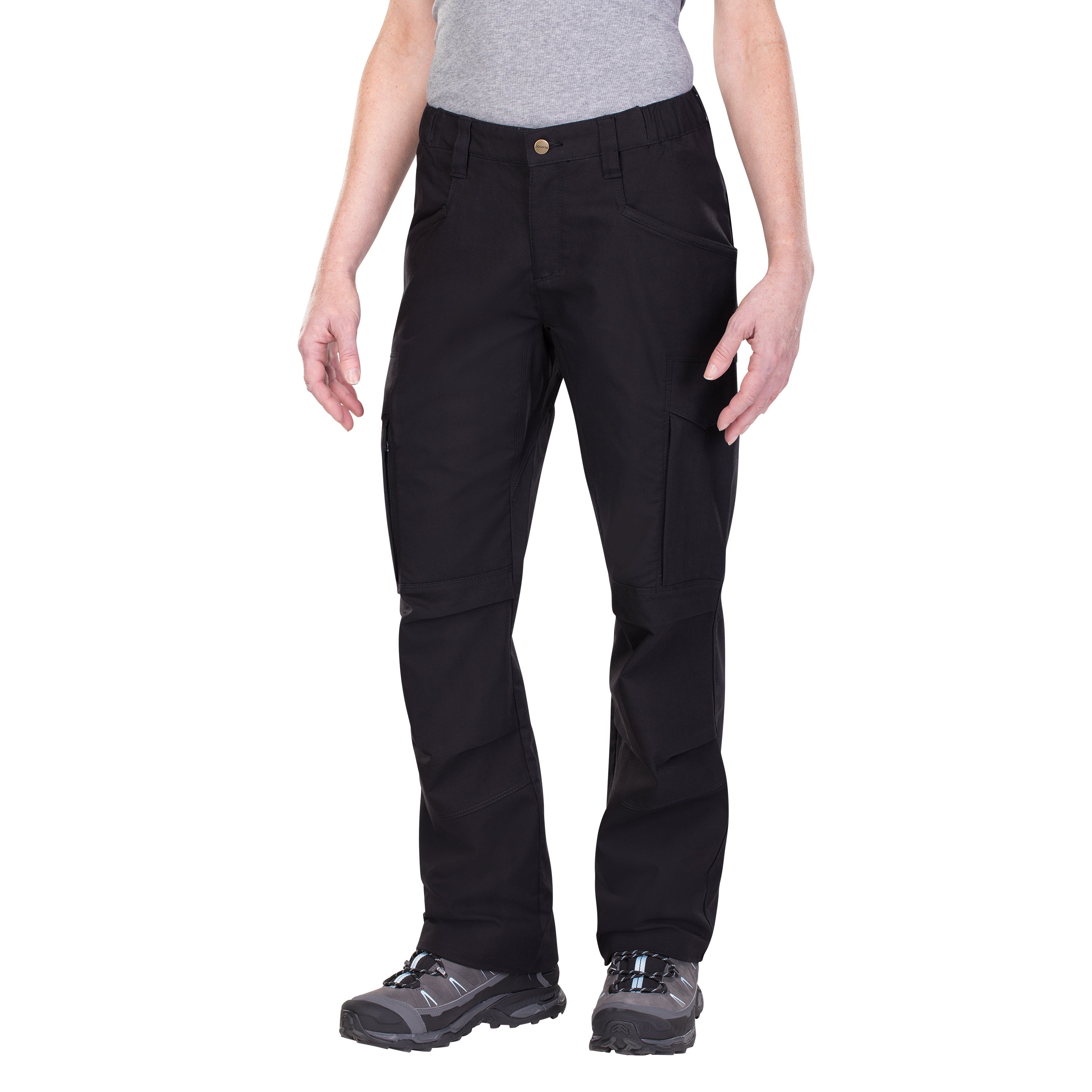 Product shot showing a pair of black women's tactical pants with reinforced knees and multiple pockets featuring a brass button and light blue accents on gray hiking boots against a white background