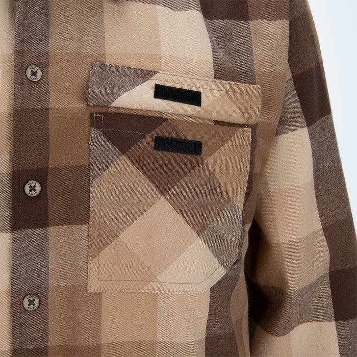Close-up of a brown and beige plaid flannel shirt featuring two flap pockets with black velcro closures and button details