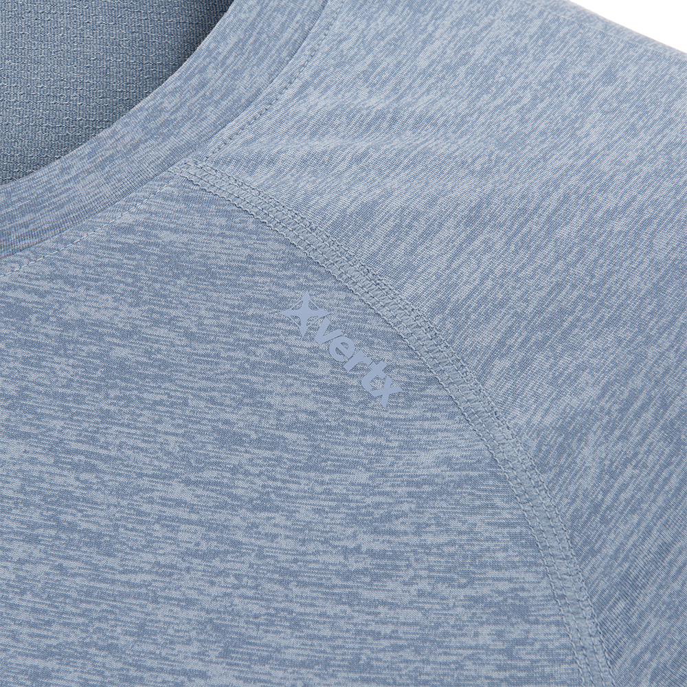 Close-up of a Vertx heather blue performance shirt showcasing its soft texture, subtle heathered pattern, and the brand's star logo