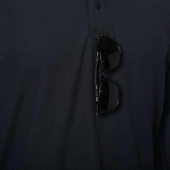 Product shot of dark-framed Boss sunglasses hanging from a dark blue polo shirt pocket showing the Boss logo and CE marking with subtle texturing on the shirt