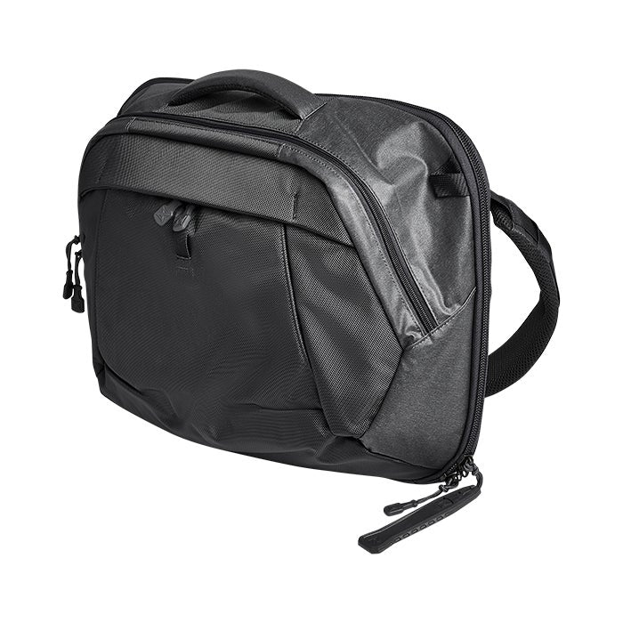 Product shot of a black Peak Design Everyday Sling, featuring a top handle, adjustable strap, and multiple zippered compartments showing textured fabric and subtle reflective details