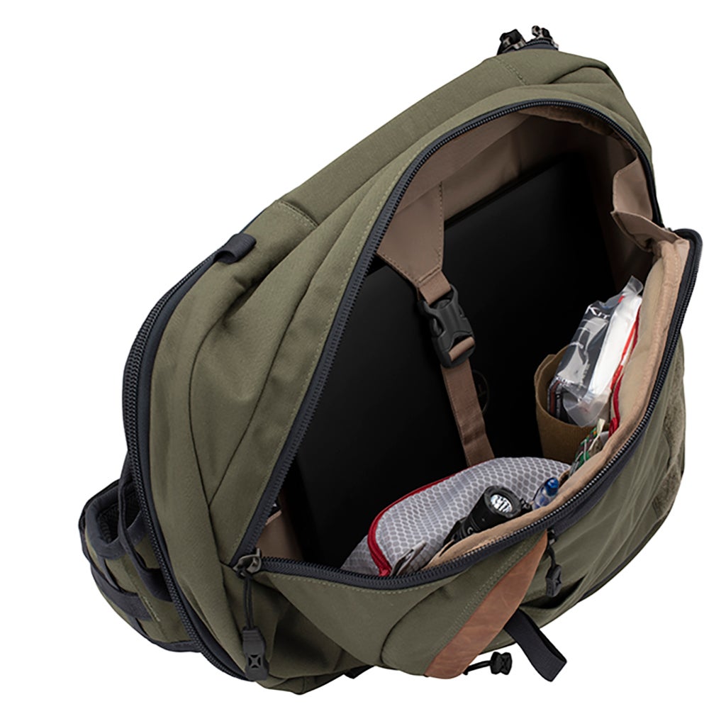Product shot of a green and tan sling bag showing interior organization with a laptop first aid kit and other accessories