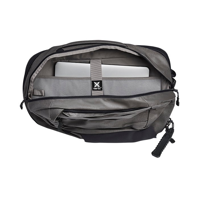Product shot showing the interior of a Vertx duffel bag featuring a laptop sleeve, gray fabric, and a black bottom compartment with a unique side release buckle