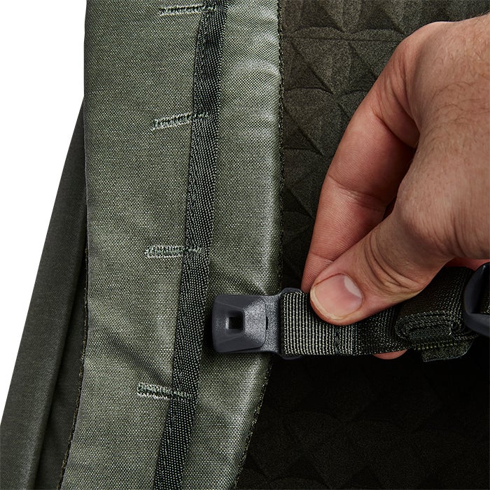 Close-up product shot of a green backpack showing a detail of its adjustable straps a black plastic buckle and textured fabric