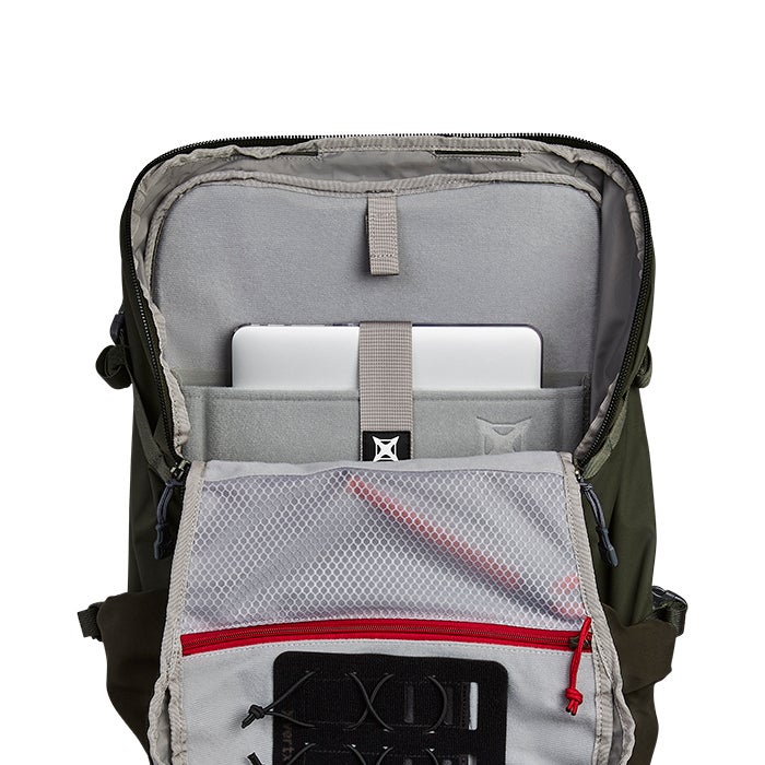 Product shot of a Peak Design Everyday Backpack showcasing its olive green exterior, grey padded laptop sleeve, red zipper accents and organized interior mesh pocket