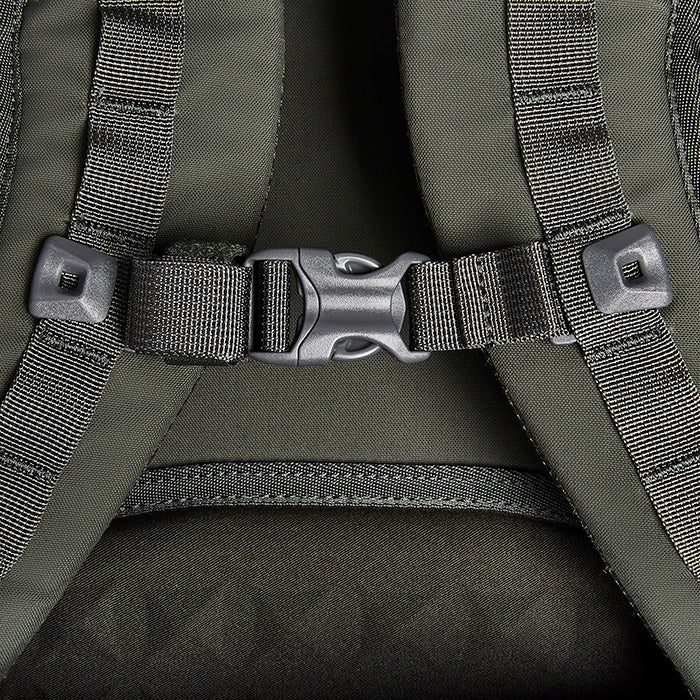 Close-up of a dark olive green backpack detail showing adjustable straps a plastic buckle and a stitched seam