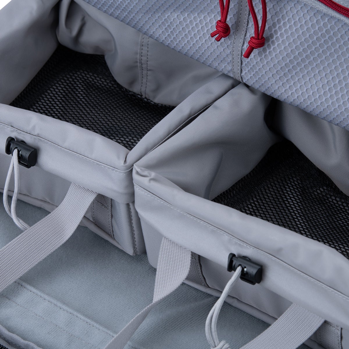 Product photography showing a gray fabric bag interior with two removable compartments featuring gray fabric, red drawstrings, and black mesh lining