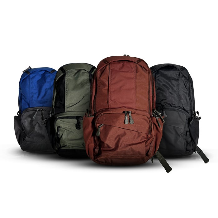 Product shot showing four backpacks in blue green brown and black against a white background featuring durable fabric and multiple zippered compartments
