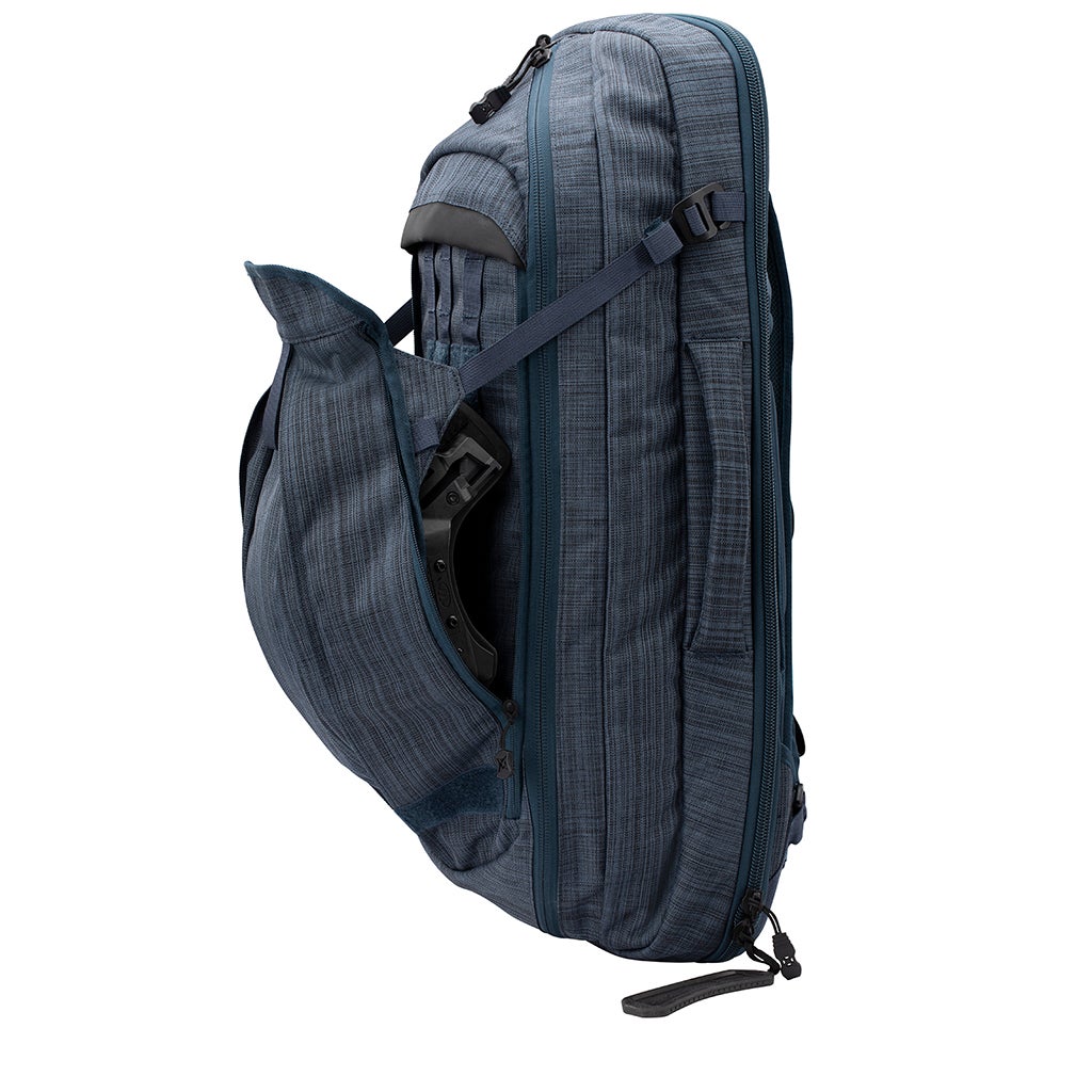 Product shot of a blue Osprey Farpoint 40 travel backpack showing a side profile with a helmet in a side pocket and featuring multiple zippered compartments and adjustable straps