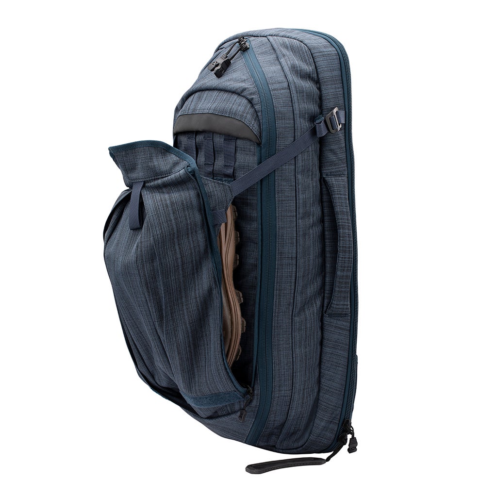 Product shot of a dark blue carry-on travel backpack featuring a shoe compartment a side handle and multiple zippered pockets showcasing a textured fabric and sleek design
