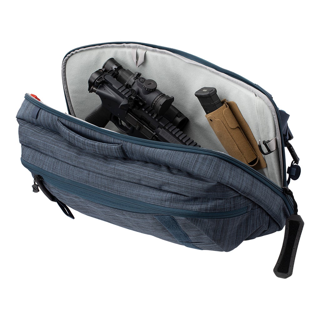 Product photo showing a blue textile gun range bag containing a black rifle with scope a tan magazine pouch and red zipper pulls