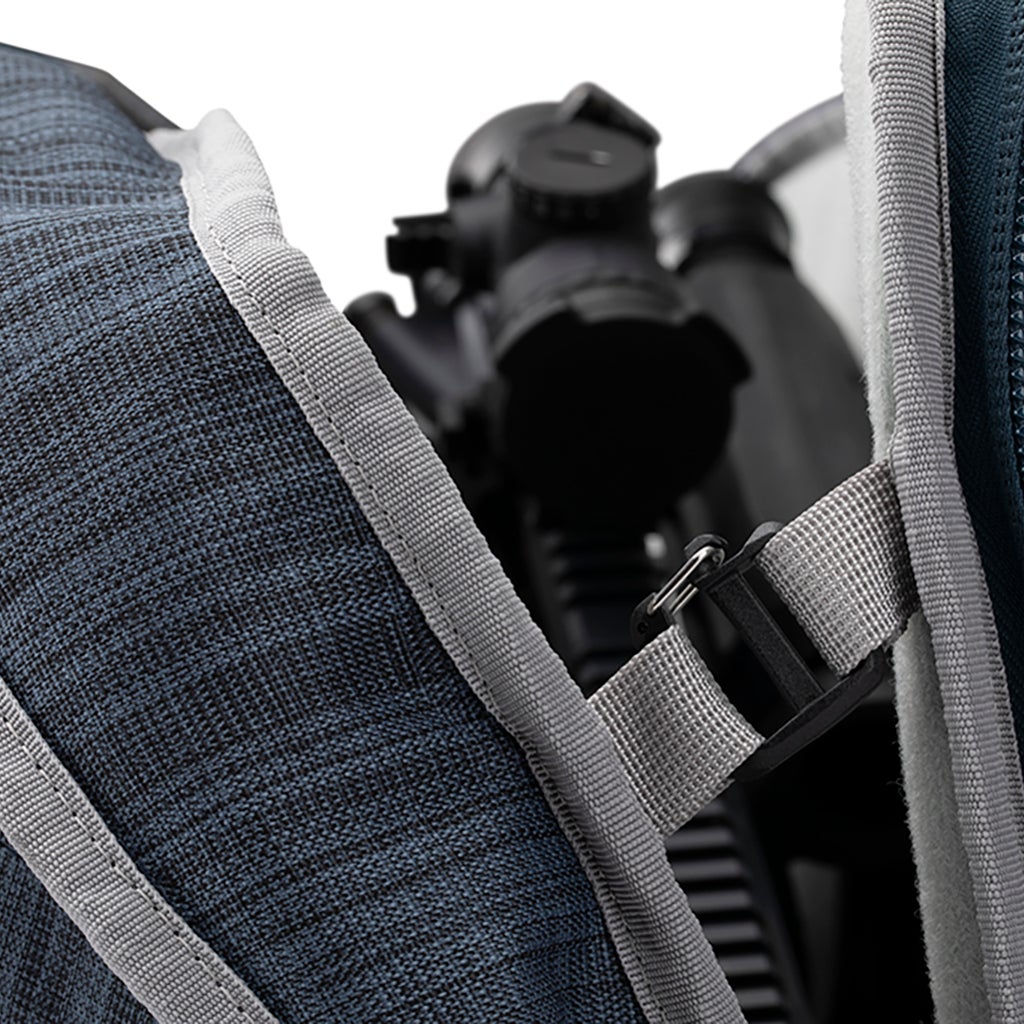 Close-up photograph of a dark blue tripod case with grey accents and a black tripod partially visible featuring a textured fabric a light grey strap and a plastic buckle