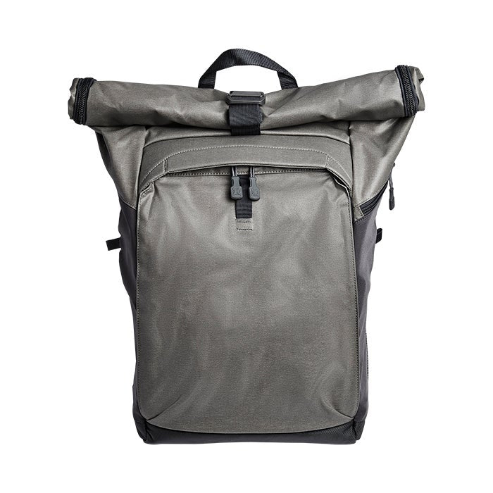 Product shot of a gray roll-top backpack featuring black accents, a top handle, and dual zipper pulls on the main compartment