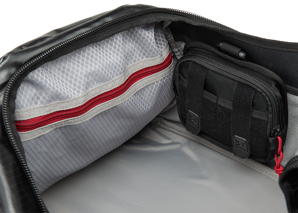 Product shot showing the interior of a black bag with red zippers grey lining and a smaller black accessory pouch with molle webbing