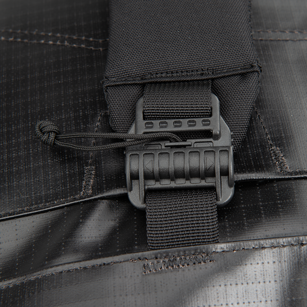 Close-up product shot of a black bag featuring a textured fabric adjustable strap with a plastic buckle and a knotted cord detail