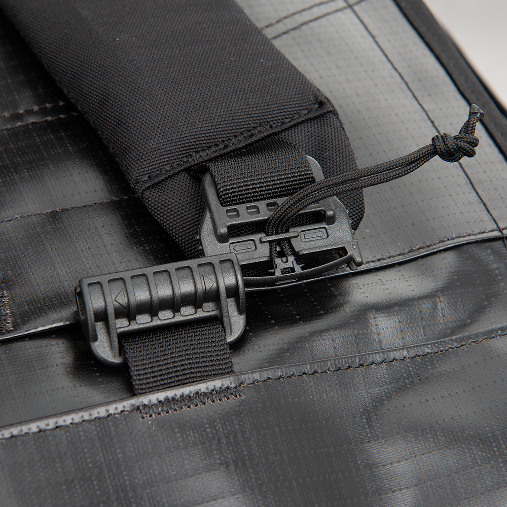 Close-up product shot of a black bag featuring adjustable straps with plastic buckles and a cord with a knot detail showing high-quality stitching and textured fabric