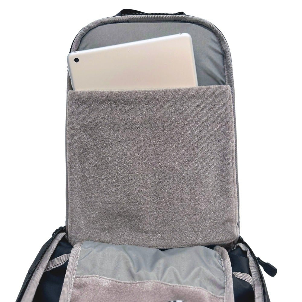Product shot showing a gray padded tablet sleeve inside a black backpack with zipper pulls and soft gray lining