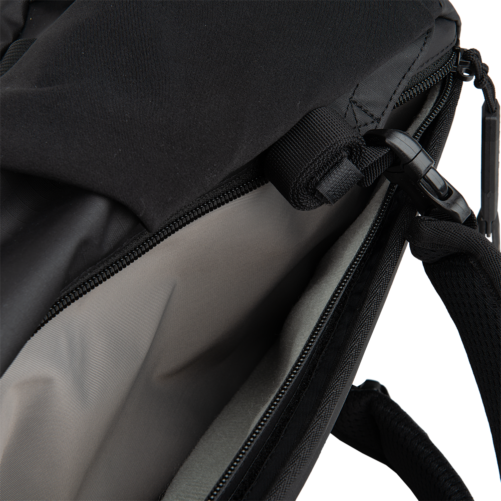 Product shot of a black backpack interior showing a gray padded compartment a black zipper and a black clasp