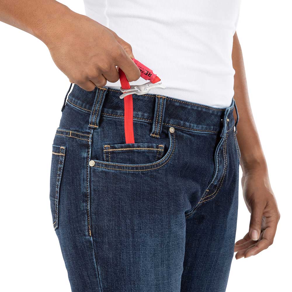 Product shot showing a person using a red RE/DONE belt extender clipped to dark wash jeans with visible front pockets and belt loops