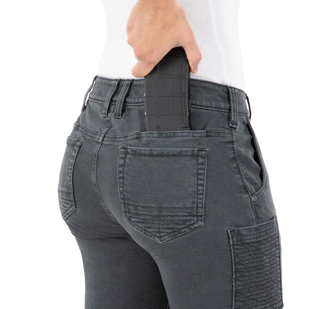 Product shot showing a woman's backside in dark gray jeans with a black magazine partially inserted in the back pocket featuring subtle stitching details and reinforced seams